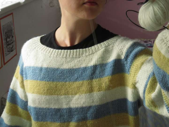 Raglan sweater with wide stripes in white, blue and yellow, over a black shirt clearly showing that the neckline is too wide