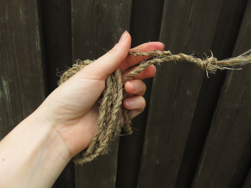 A length of rough cordage wrapped around my left hand, with the ends held between fingers. 